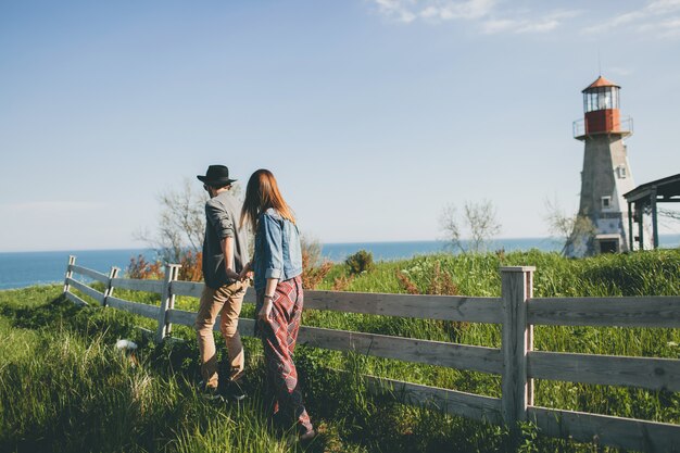 Pareja joven inconformista estilo indie enamorado caminando en el campo