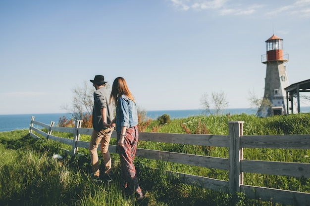 Pareja joven inconformista estilo indie enamorado caminando en el campo