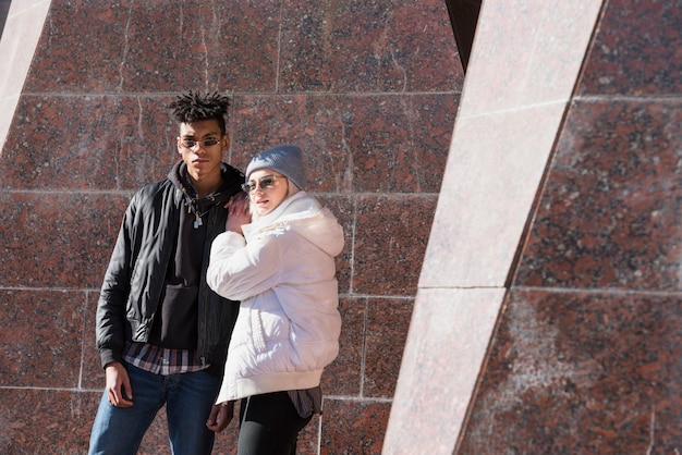 Pareja joven interracial moderna con gafas de sol mirando a cámara