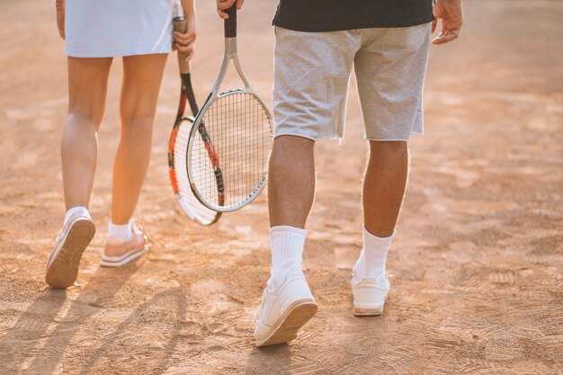 Pareja joven jugando al tenis en la cancha, pies de cerca