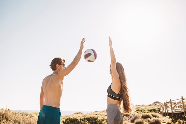 Foto gratuita pareja joven jugando al voleibol en la playa