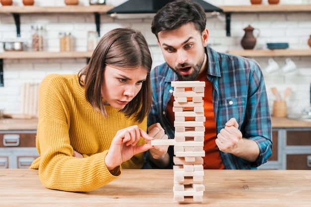 Pareja joven jugando el bloque apilado de madera en la mesa