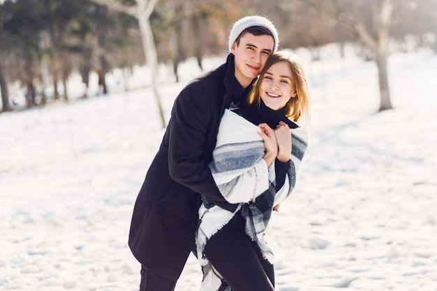 Pareja joven jugando en un campo cubierto de nieve