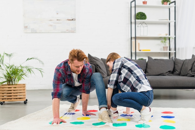 Pareja joven jugando el juego de puntos de color en la sala de estar en casa