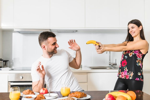 Foto gratuita pareja joven jugando con plátano en la cocina