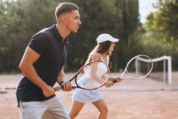 Pareja joven jugando tenis en la cancha