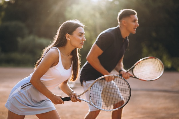 Foto gratuita pareja joven jugando tenis en la cancha