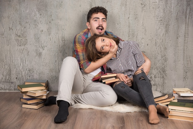 pareja joven juguetonamente peleando entre sí junto a los libros