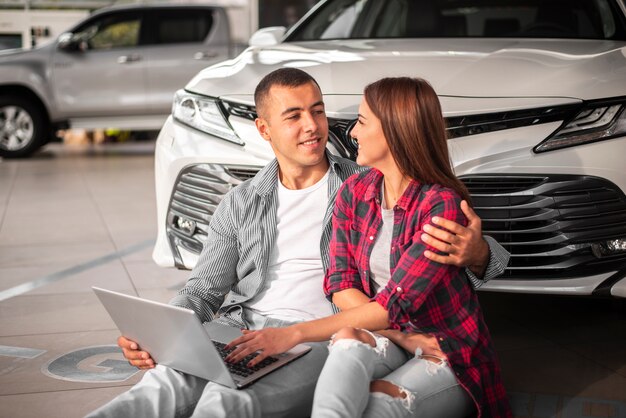 Pareja joven junto en concesionario de automóviles