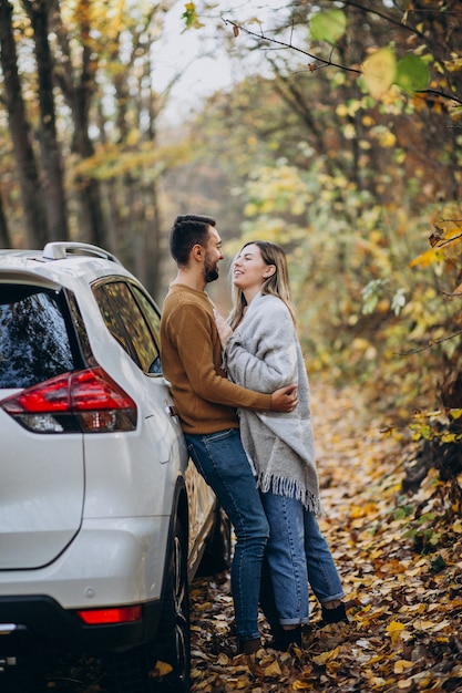 Pareja joven junto en el parque junto al coche