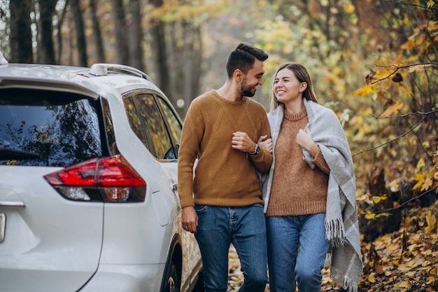 Pareja joven junto en el parque junto al coche