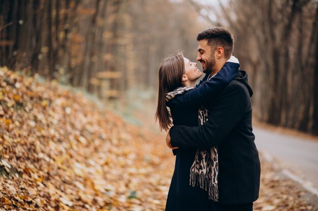 Pareja joven juntos caminando en un parque de otoño