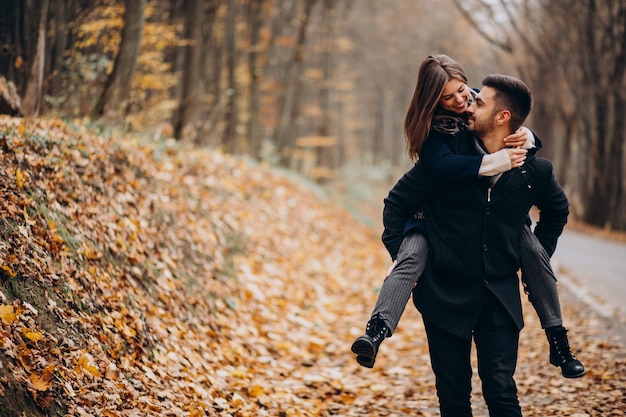 Pareja joven juntos caminando en un parque de otoño