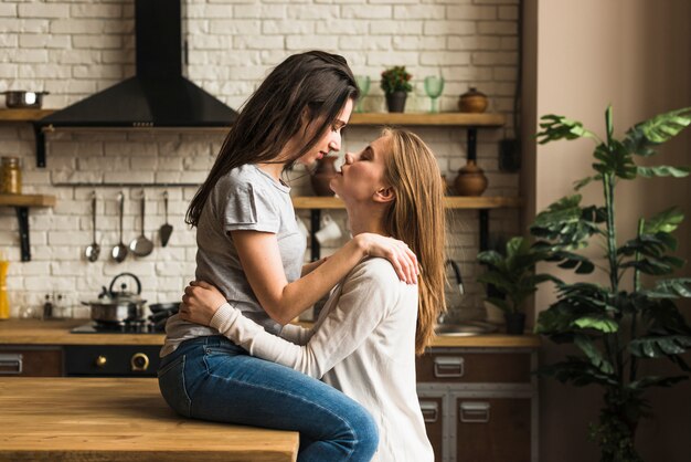 Pareja joven lesbiana apasionada amándose en la cocina