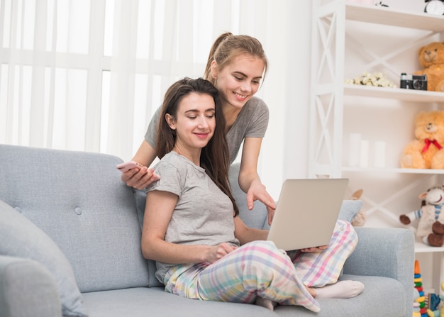 Pareja joven lesbiana sonriente mirando portátil