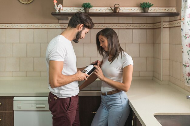 Pareja joven leyendo cucharón en botella de vino