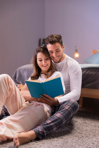 Pareja joven leyendo juntos en la cama