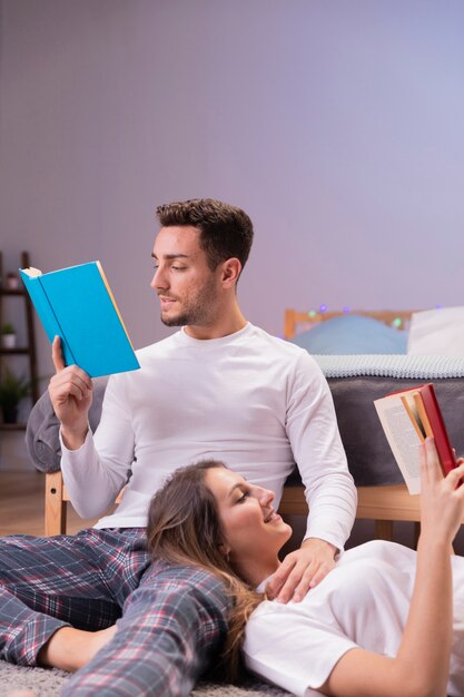 Pareja joven leyendo juntos en la cama