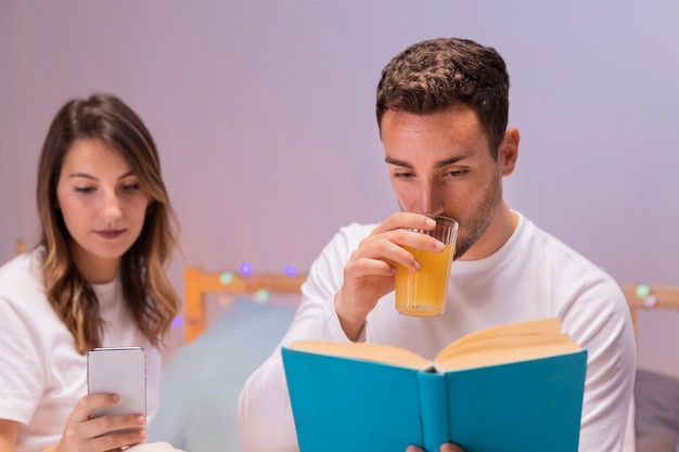 Pareja joven leyendo juntos en la cama