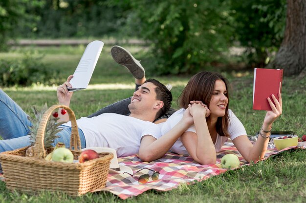 Pareja joven leyendo libros en la naturaleza