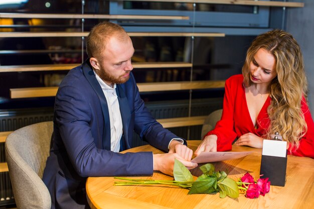 Pareja joven leyendo menú en restaurante