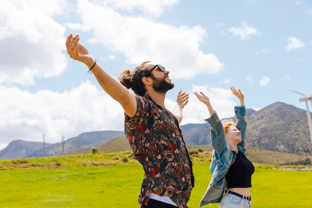 Pareja joven con las manos en alto en la naturaleza