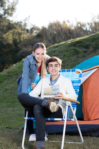 Pareja joven con un mapa junto a la tienda de campaña