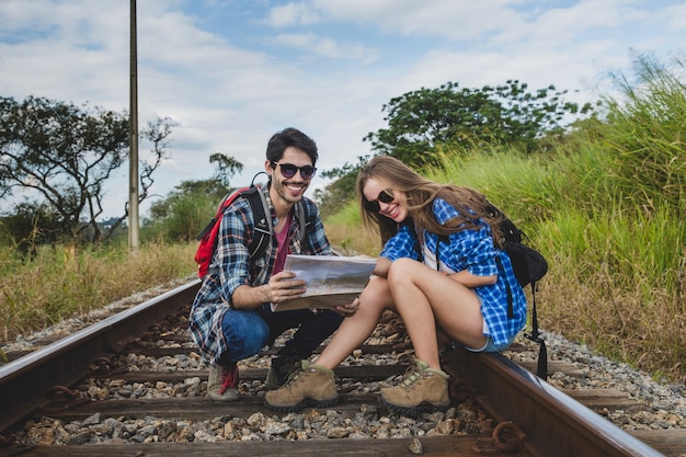 Pareja joven con mapa en vías de tren