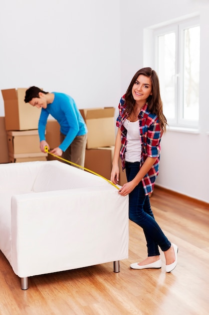 Foto gratuita pareja joven midiendo el sofá en su nuevo apartamento