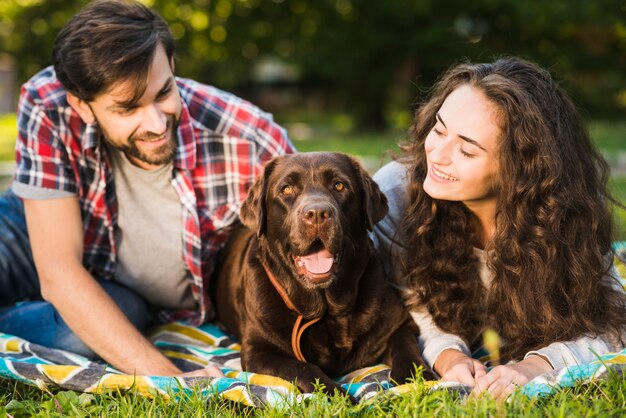 Pareja joven mirando a su perro lindo en el parque