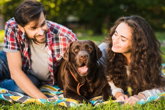 Pareja joven mirando a su perro lindo en el parque