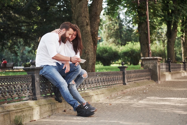 Pareja joven mirando un teléfono inteligente en un día soleado en la ciudad