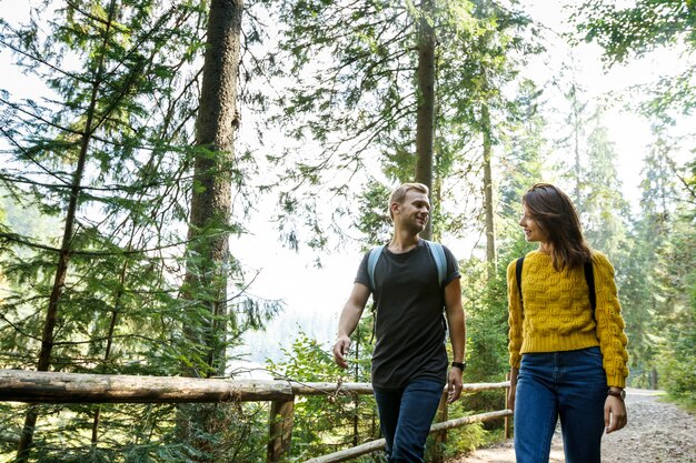 Pareja joven mirándose, caminando en el bosque de montaña