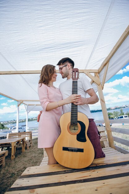 Pareja joven mirándose a la cara y sujetando una guitarra