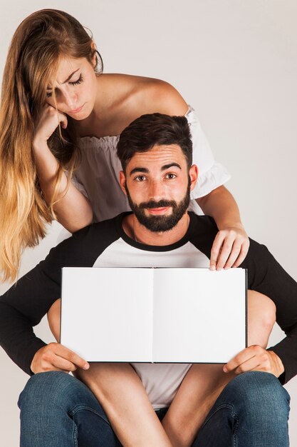 Pareja joven mostrando libro en blanco