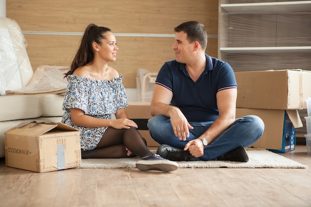 Pareja joven moviéndose en un nuevo hogar. Hombre y mujer desembalaje de cosas frágiles.