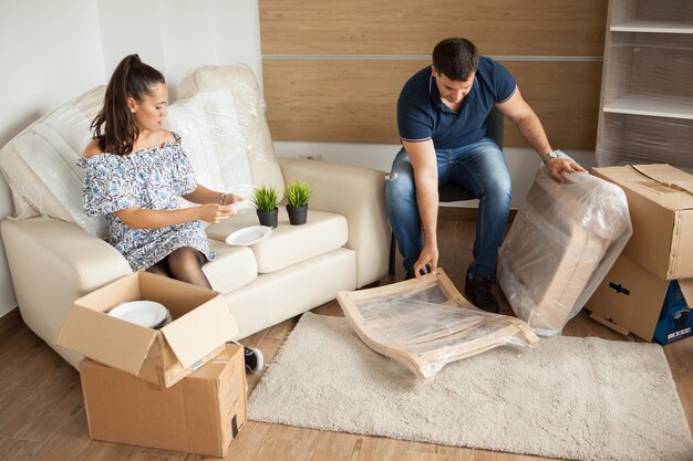 Pareja joven mudándose a casa nueva y desembalaje de cajas de cartón. Casi terminado de mudarse.