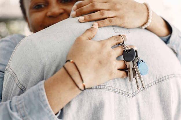 Pareja joven mudándose juntos al nuevo hogar. Pareja afroamericana con cajas de cartón. Mujer mantenga llaves.