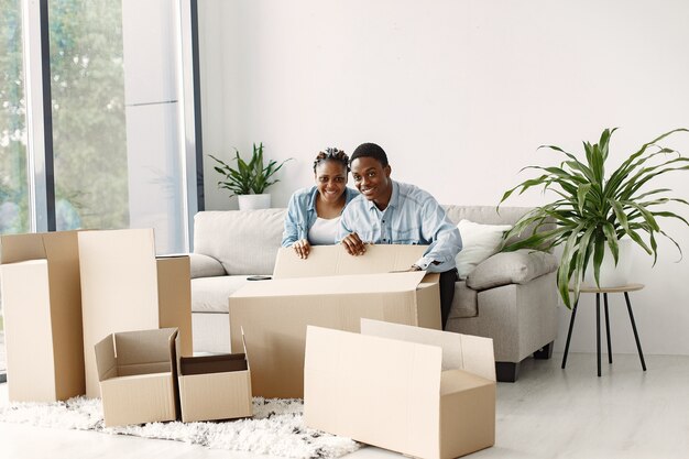 Pareja joven mudándose juntos al nuevo hogar. Pareja afroamericana con cajas de cartón.