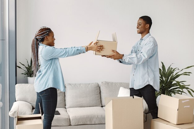 Pareja joven mudándose juntos al nuevo hogar. Pareja afroamericana con cajas de cartón.