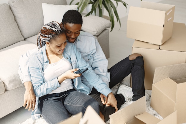 Pareja joven mudándose juntos al nuevo hogar. Pareja afroamericana con cajas de cartón.