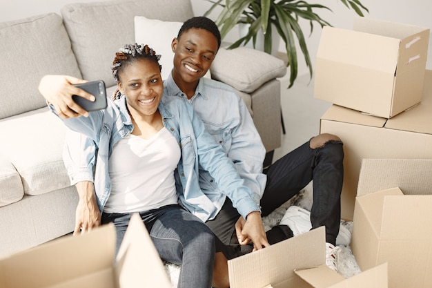 Pareja joven mudándose juntos al nuevo hogar. Pareja afroamericana con cajas de cartón.