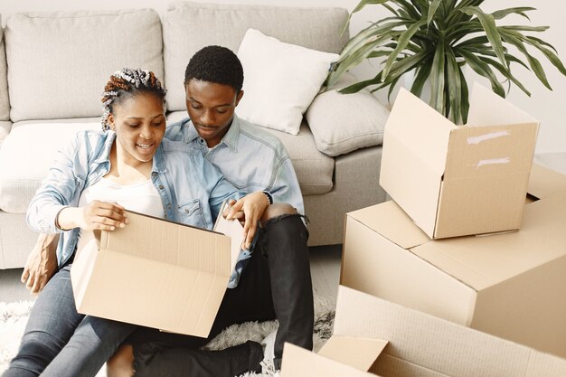 Pareja joven mudándose juntos al nuevo hogar. Pareja afroamericana con cajas de cartón.