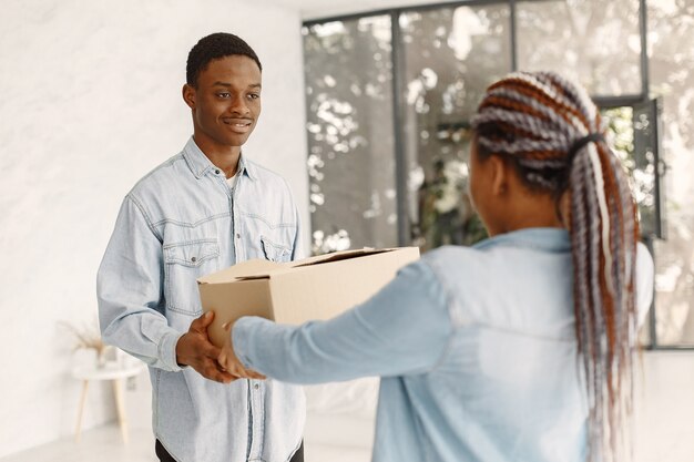 Pareja joven mudándose juntos al nuevo hogar. Pareja afroamericana con cajas de cartón.