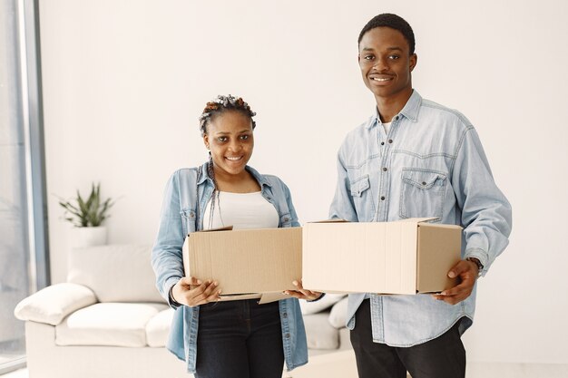 Pareja joven mudándose juntos al nuevo hogar. Pareja afroamericana con cajas de cartón.