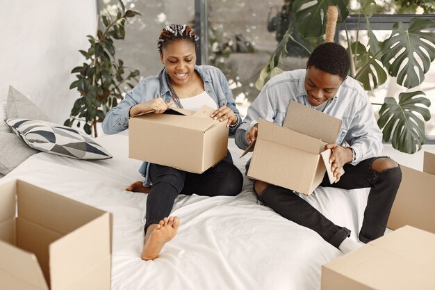 Pareja joven mudándose juntos al nuevo hogar. Pareja afroamericana con cajas de cartón.