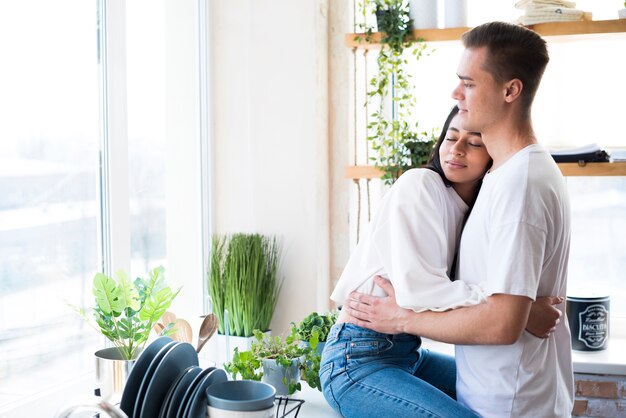 Pareja joven multiétnica en el amor que abraza en cocina