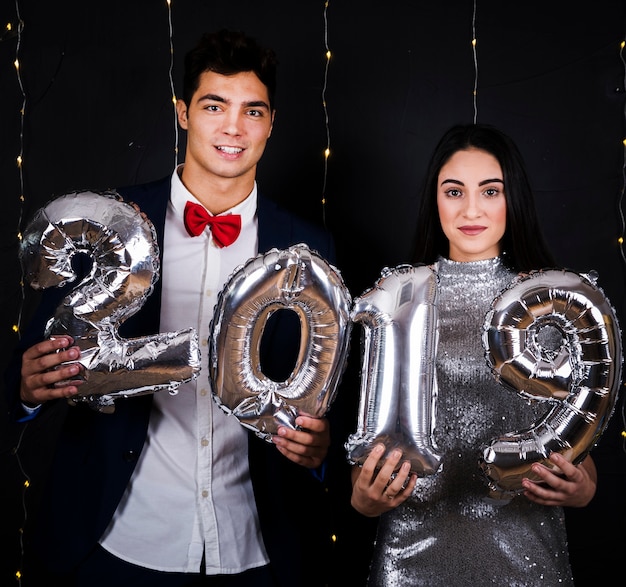 Foto gratuita pareja joven con números de globos