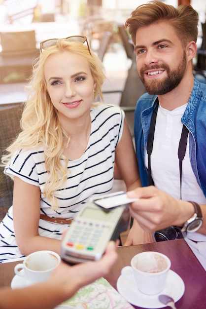 Pareja joven pagando por el café