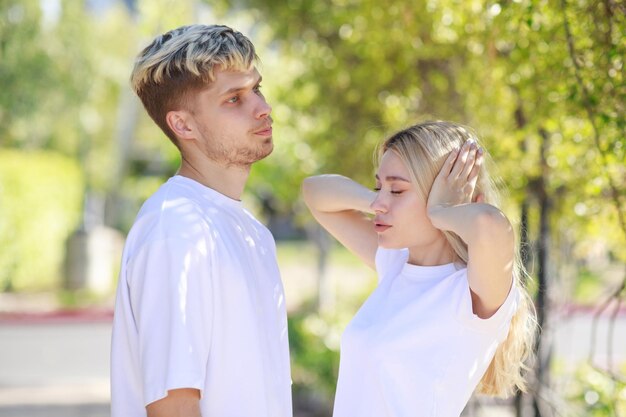 Pareja joven parada en el parque y sintiéndose enojada Foto de alta calidad